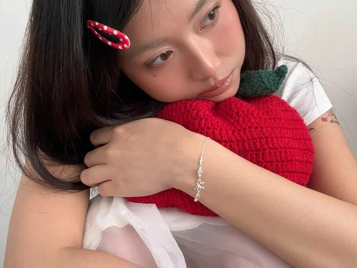 Cô gái ôm chú gấu bông đỏ, cổ tay đeo lắc tay bạc, nụ cười rụt rè — tâm lý ngập ngừng của giai đoạn crush