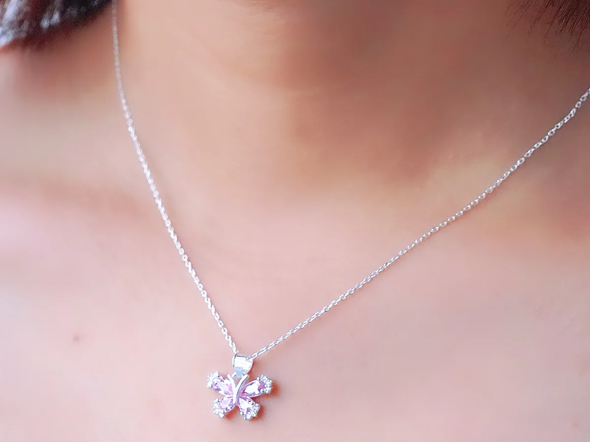 Dây chuyền bạc mặt hoa nhỏ đeo trên cổ — một mô-típ duy nhất làm điểm nhấn