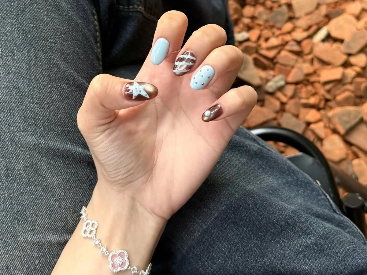 Bàn tay đeo lắc tay bạc buông trên vạt quần jeans — kiểu kỷ vật đi theo người ta vào cả những ngày rất đỗi bình thường