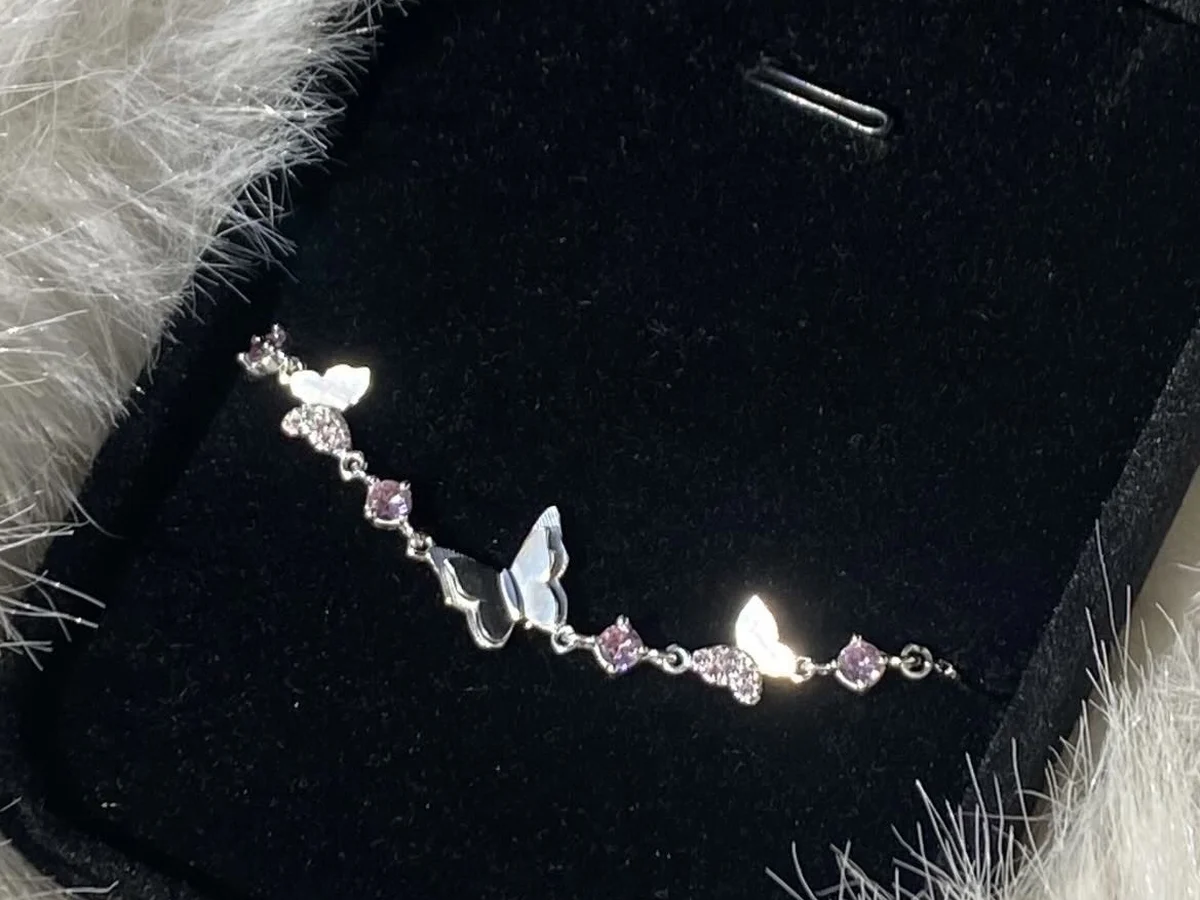 Lắc tay bạc đính đá và charm bướm — nhóm trang sức chỉ nên làm sáng bằng nước rửa bạc, không chà mạnh