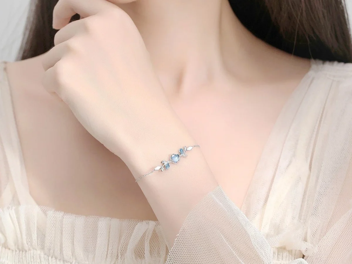 Lắc tay bạc đá moonstone trên cổ tay, đi cùng áo voan mỏng màu kem