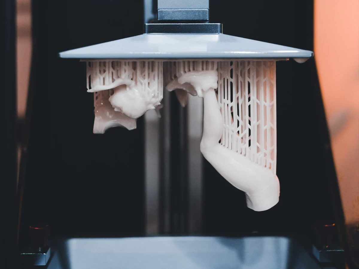 Chi tiết vừa in 3D còn dính giàn đỡ, treo dưới bàn in của máy in resin