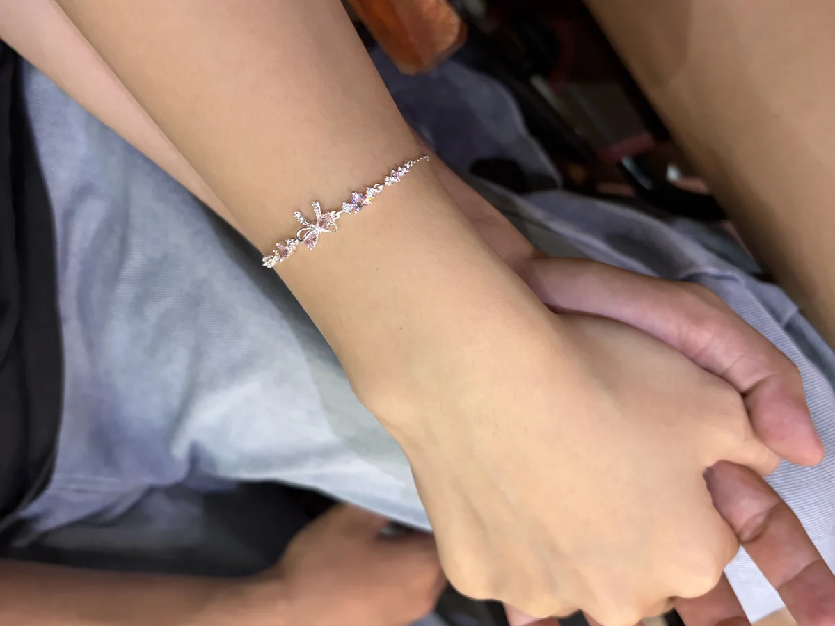 Hai bàn tay chạm nhau, cổ tay nàng đeo lắc tay bạc đính đá hồng — món quà tặng người yêu được đeo mỗi ngày