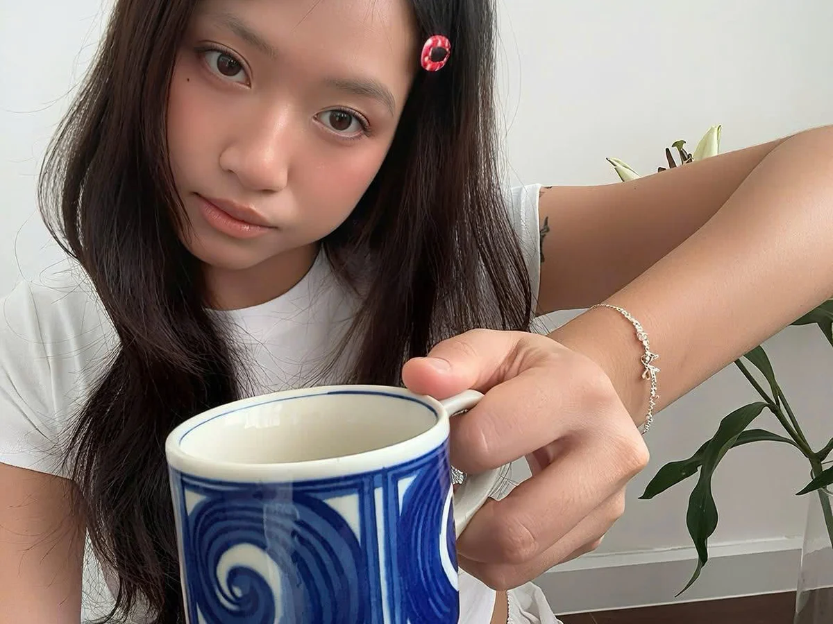 Cô gái trẻ cầm tách cà phê, cổ tay đeo lắc tay bạc Asimi — món quà nhẹ nhàng hợp giai đoạn tỏ tình