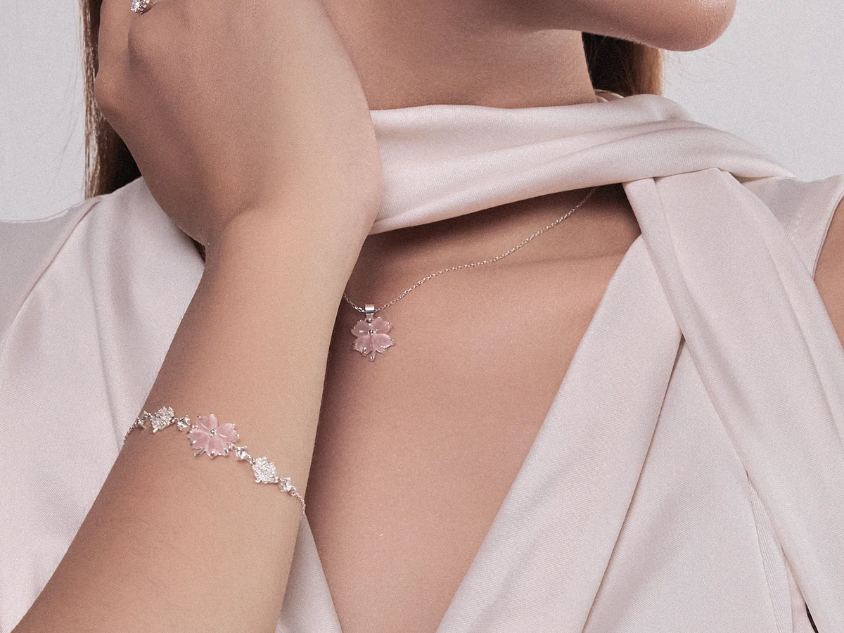 Nàng đeo set dây chuyền bạc mặt nhỏ và lắc tay bạc đồng bộ mặt hoa hồng phấn của Asimi