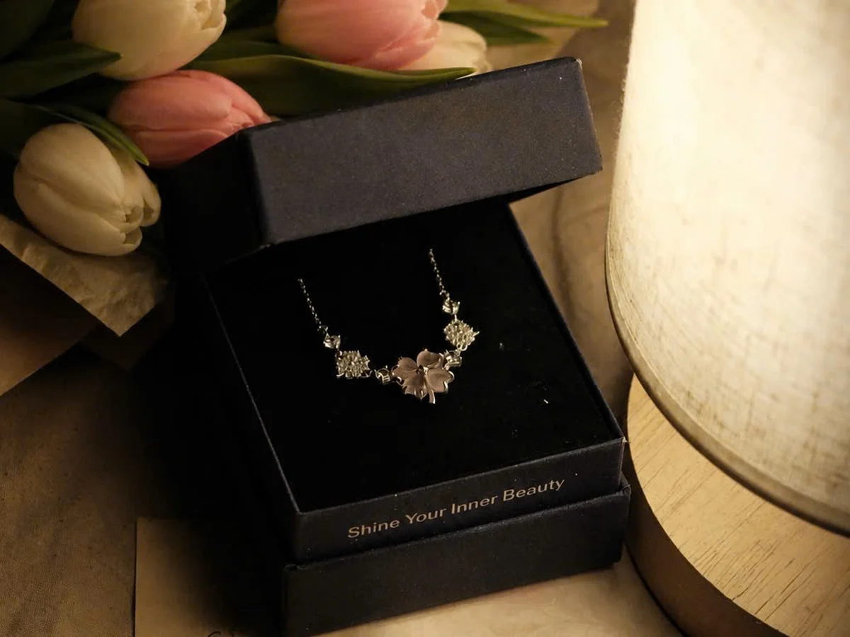 Hộp trang sức bạc Asimi bên bó tulip dưới ánh đèn ấm — khung cảnh trao quà tỏ tình ấm áp