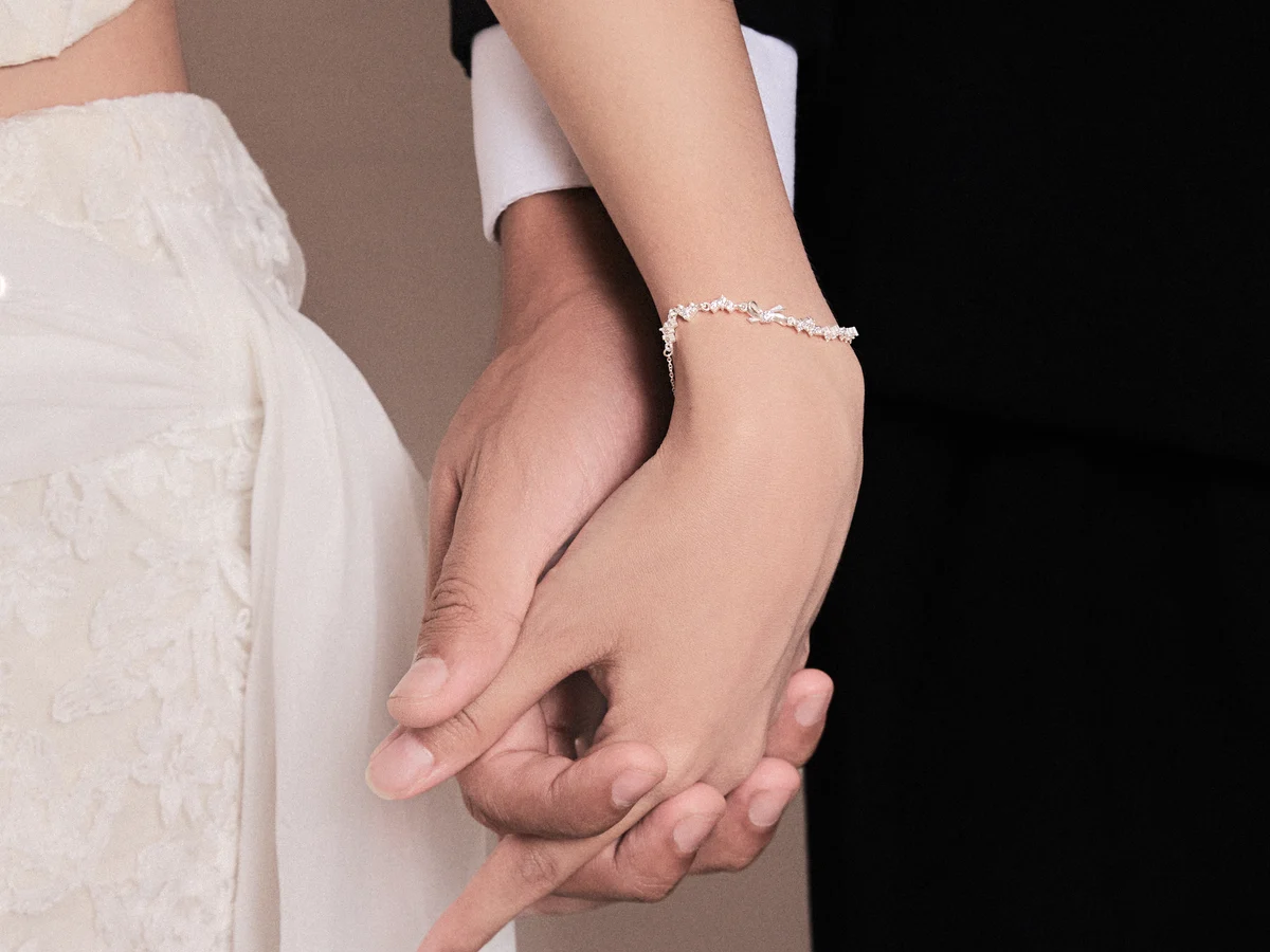 Ý nghĩa món quà tặng người yêu — đôi tay nắm nhau, cổ tay cô gái đeo lắc tay bạc Asimi